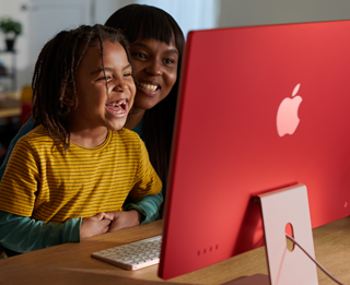 Persone di una famiglia che ridono mentre guardano insieme un programma su iMac.